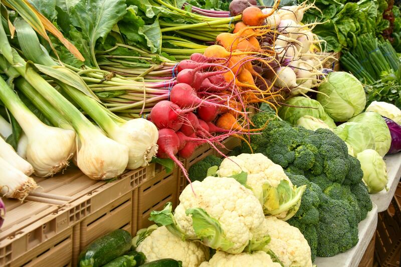 Puerros, rábanos, coliflor y brócoli frescos apilados en un puesto de mercado