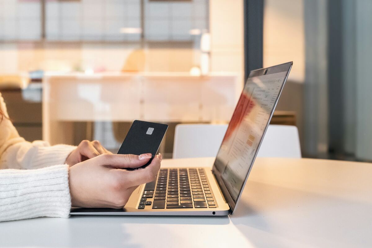 Una persona frente a una laptop sostiene una tarjeta negra con chip y sin marcas, lista para comparar opciones